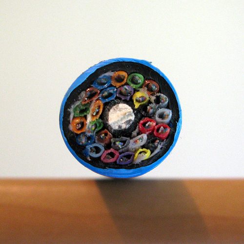 A close-up of a transverse cross-section of fibre-optic cable showing multi-coloured fibres and a chalky-coloured core.