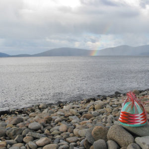 Wire basket in progress on the pebble beach at Cockle Bay Lagoon, with rainbows over Maria Island in the background.