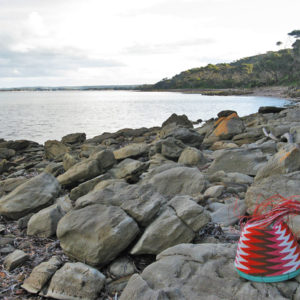 Fab-40 wire basket, with white, orange, brown and pink wires in a zig-zag pattern, on the rocky beach at American River on Kangaroo Island.