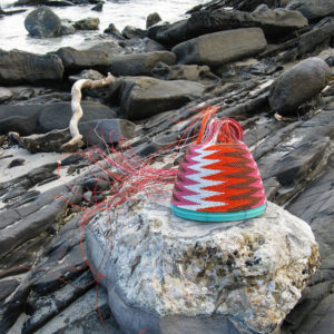 Brightly coloured telephone-wire basket on glistening rocks at Antechamber Bay, Kangaroo Island