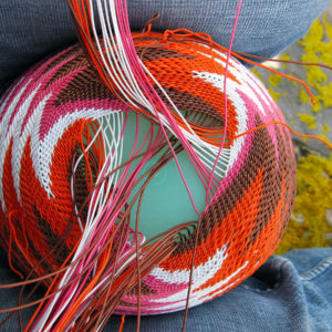 Close-up of weaving the base of a telephone wire basket. Sitting on rocks covered in chrome yellow lichen at Antechamber Bay, Kangaroo Island.