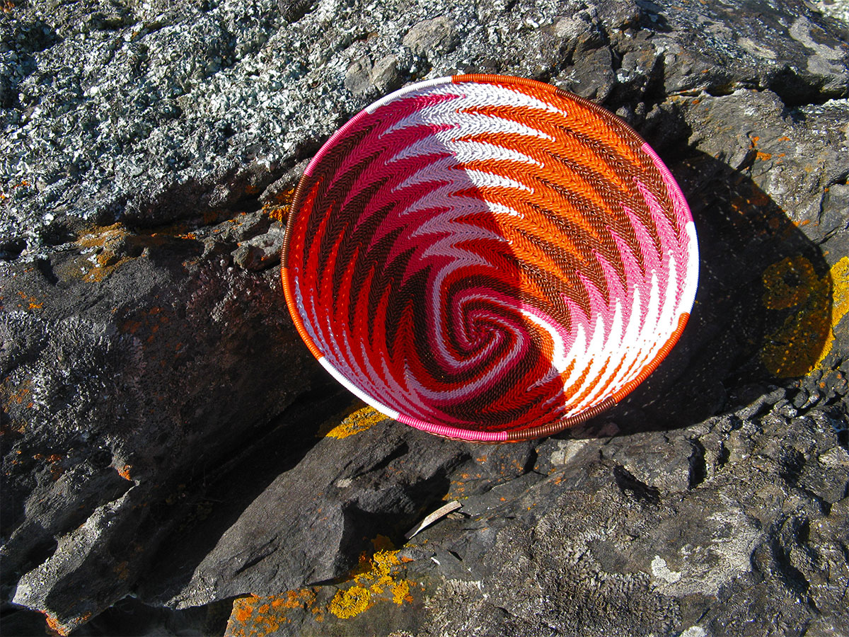 Finished chevron-patterned telephone-wire basket on lichen-covered coastal rocks at Penneshaw, Kangaroo Island.
