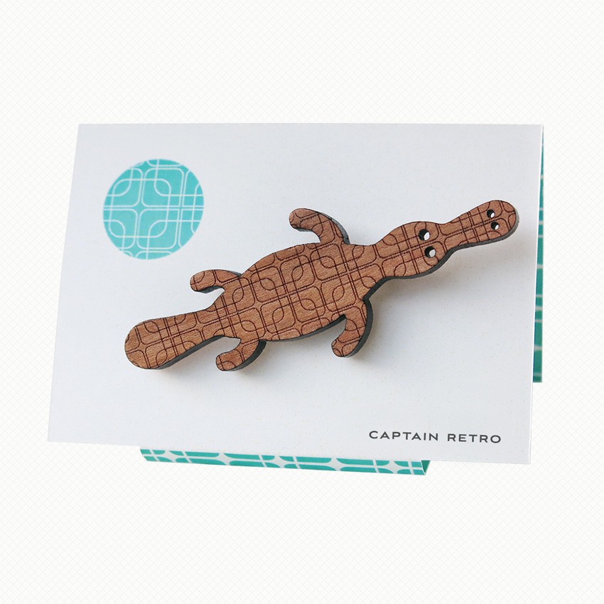 Captain Retro Platypus brooch in myrtle wood veneer Duck-billed platypus brooch in Tasmanian Myrtle wood veneer with a delicate laser-engraved retro pattern of overlapping squares