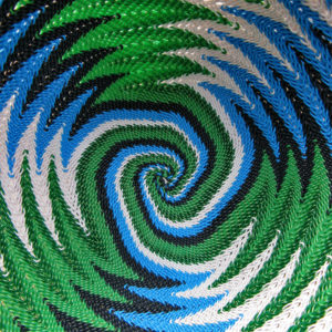 Close-up of the inside of a telephone wire basket, in a spiralling, chevron pattern of white, blue, black and metallic green wires.