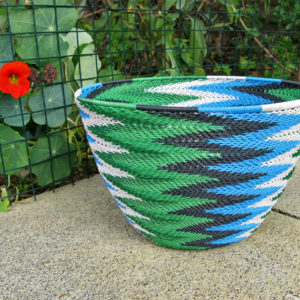 A completed telephone wire basket in a chevron pattern of blue, black, white and metallic green wires.