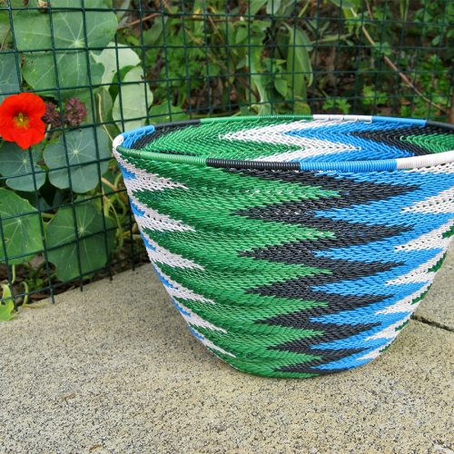 A completed telephone wire basket in a chevron pattern of blue, black, white and metallic green wires.