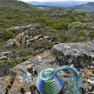 Wire basket on lichen covered rocks, looking out to Lake Daphne from the foot of Wyld's Craig in Tasmania's South-West.
