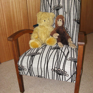A soft toy monkey and a teddy bear placed together on an armchair