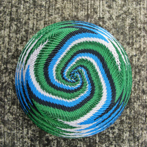 Close-up of the underside of a completed telephone-wire basket, in a spiralling pattern of white, blue, black and green wires.