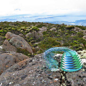 Telephone-wire basket on lichen-covered rocks on Mt Wellington, Tasmania, with the Derwent Estuary in the background.