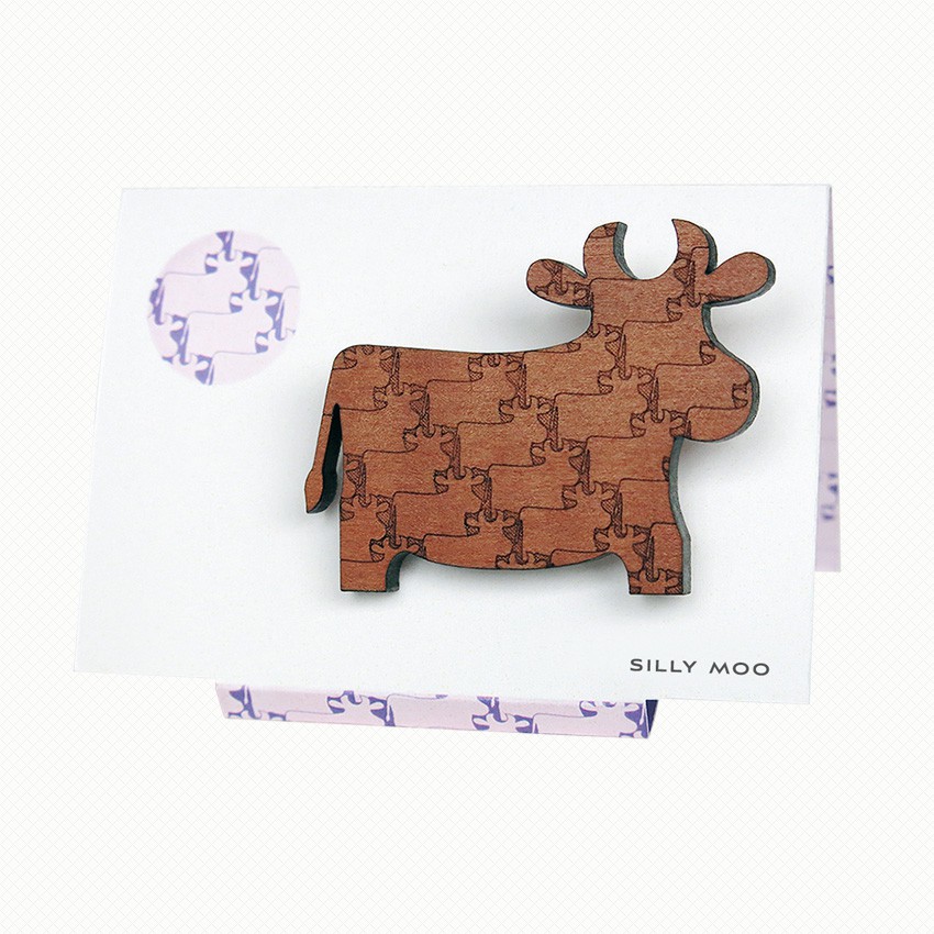 Silly Moo brooch in myrtle wood veneer Cow brooch in Tasmanian Myrtle wood with a delicately engraved pattern of overlapping cows, on an easel-style card with a matching purple and white pattern