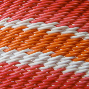 Detail of wire basket weave showing bands of red, pink, white and orange telephone wires.