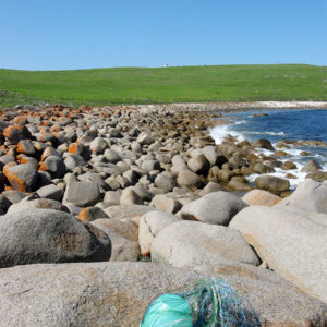 The basket in its very early stages on granite rocks at Windmill Bay, with the Cape Willoughby lighthouse in the background.